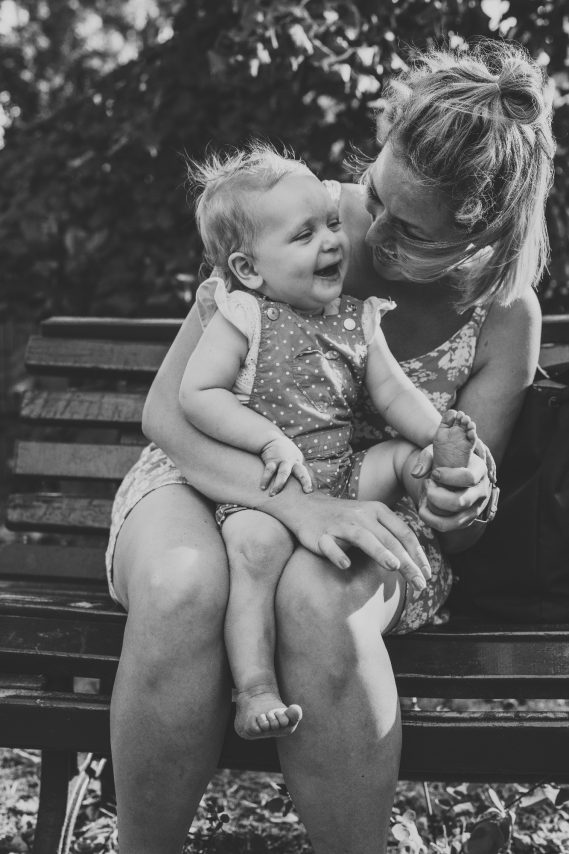 Frau mit einem Baby auf dem Schoß, beide lachen und genießen die gemeinsame Zeit.